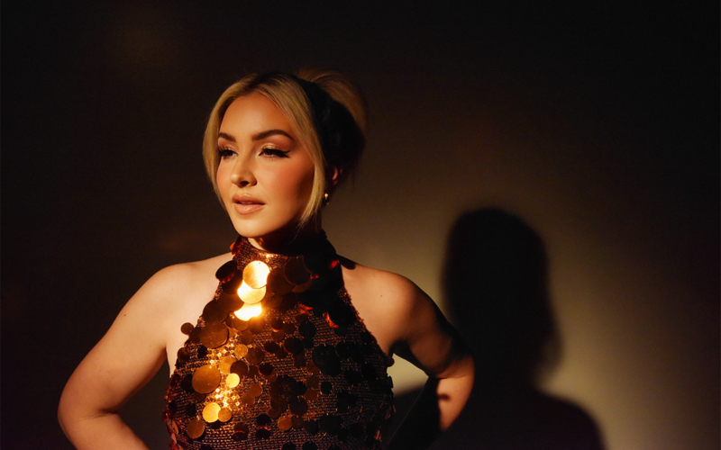 Maggie Rose wearing a gold sequined top in a promotional portrait for her album Half Moon.