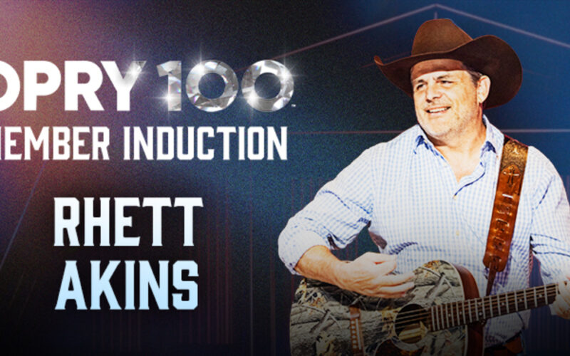 Rhett Akins holding a guitar in a graphic announcing his Grand Ole Opry member induction.