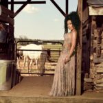 K. Michelle standing beside a wooden fence in a rural setting.